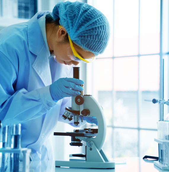 Female scientist looking into a microscope in a lab