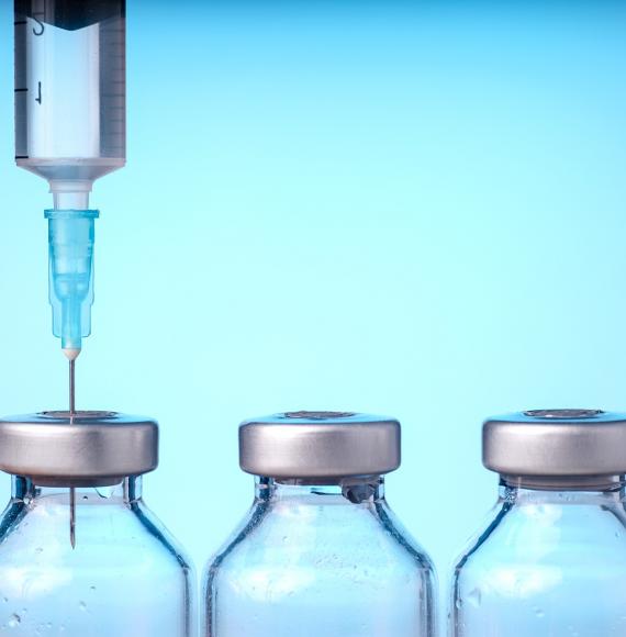 Needle injecting into the top of vaccine bottle