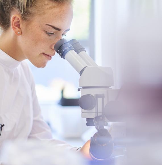 Female lab technician observing a slide in a microscope