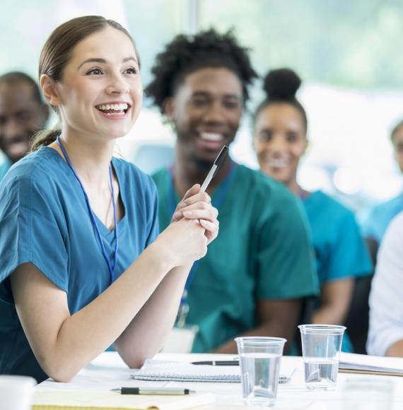 Female student nurse listening intently among a group of students