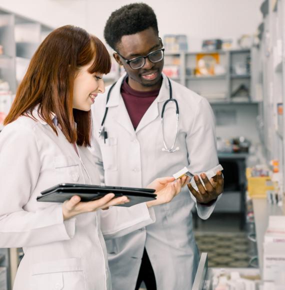 Two pharmacists reviewing a drug from their shelves