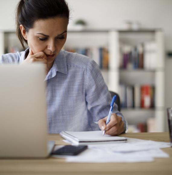 Woman making notes as she goes through e-learning materials