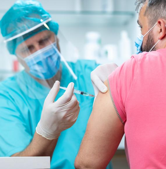 Health professional in PPE administering a vaccine jab