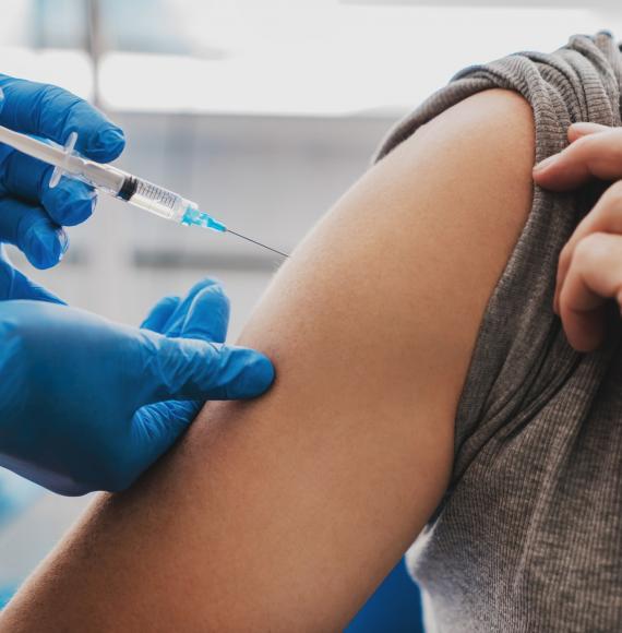 Health professional in gloves administering a vaccine jab