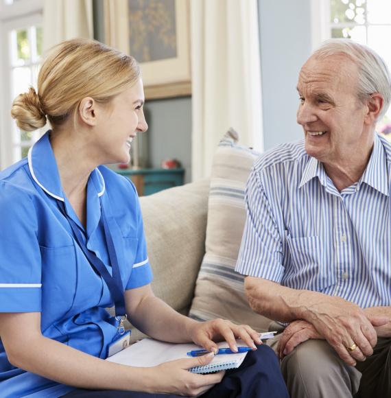 Female social care nurse sitting with an elderly man