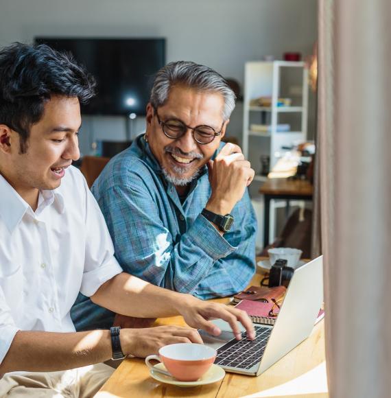 Asian father and son chatting at a laptop