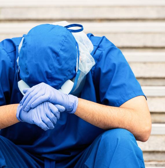 Health worker seated, head in hands, struggling with their situation