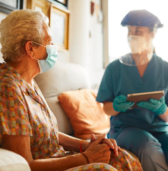 Elderly care home resident with a staff member in PPE