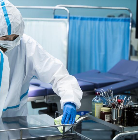 Individual in PPE wiping down a surgical surface