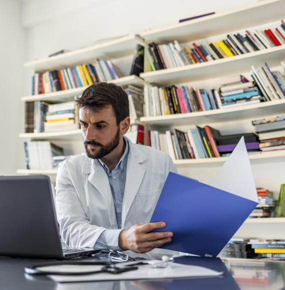 Clinician discussing a patient's record with a colleague on a laptop