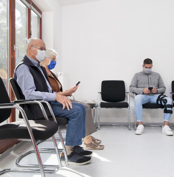 Elderly couple and a man sit in a GP waiting room