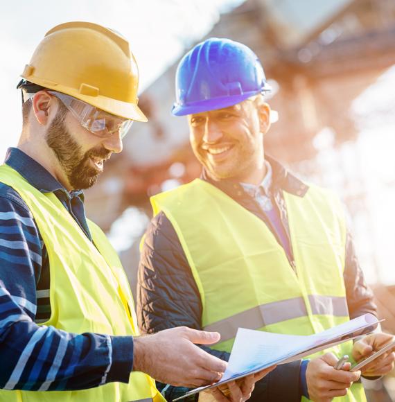 Two builders referring to plans and talking