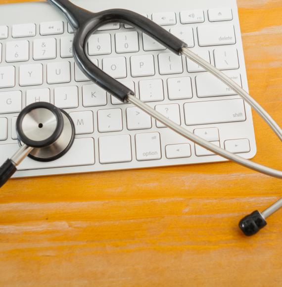 Stethoscope over computer keyboard on orange background