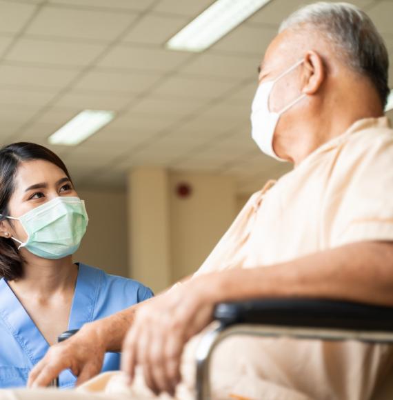 Nurse stood by patient in a wheelchair talking