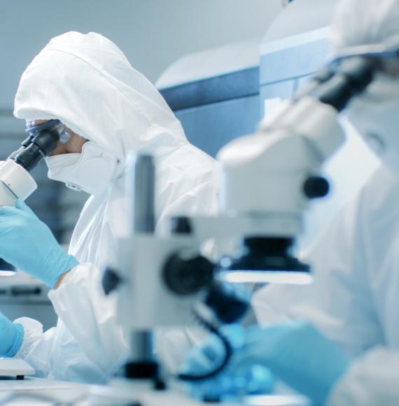 Two scientists in suits and a clean room testing pharmaceutical products