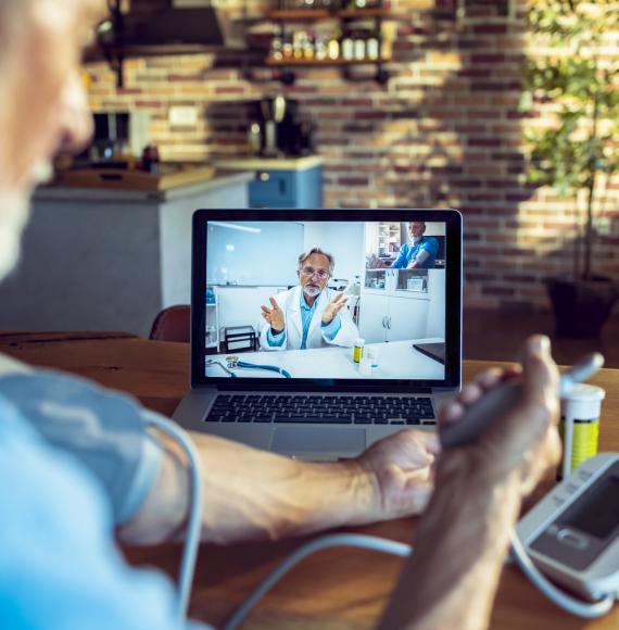 Doctor using remote video consultation with a patient taking their blood pressure