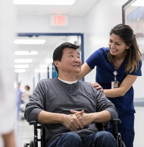 Hospital staff member pushes patient through corridor