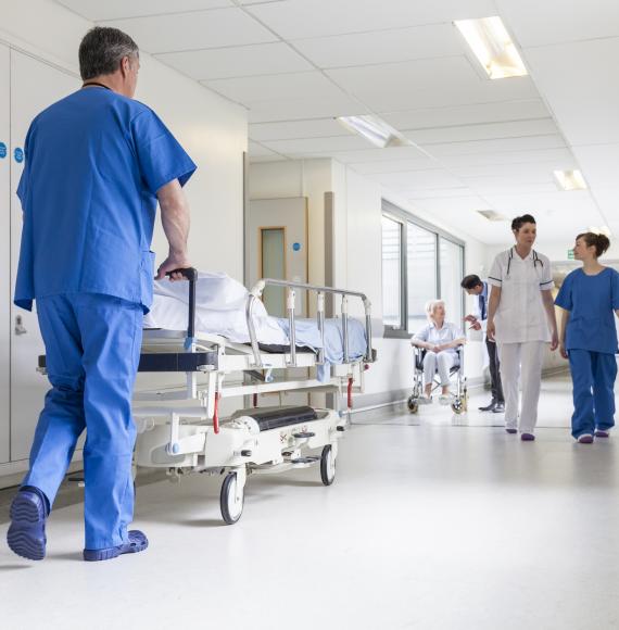 Nurse pushing hospital bed down a corridor