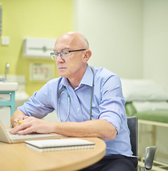 Doctor using a laptop in his practice room