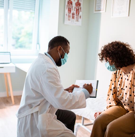 GP wearing a mask seeing to a patient