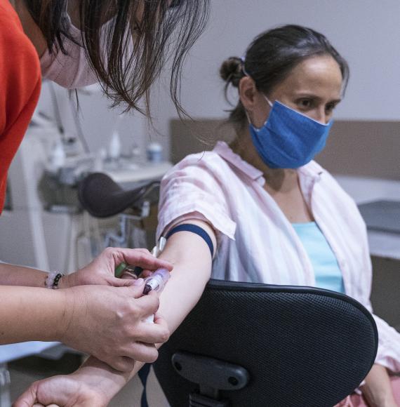 Medical practitioner drawing blood from a woman's arm