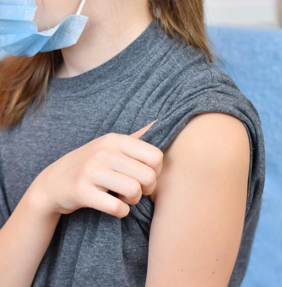 Young girl rolling up her sleeve ahead of vaccine