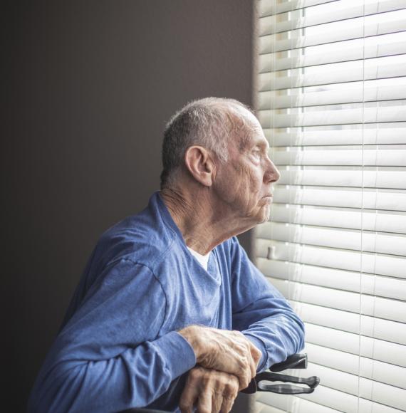 elderly man looking out window 