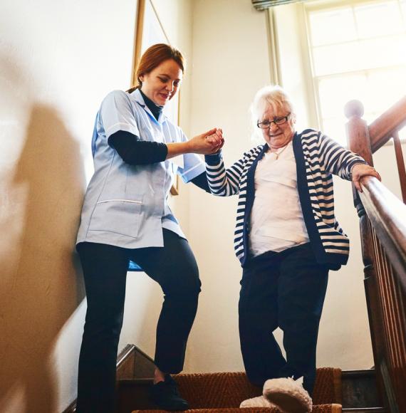 Carer helping elderly lady down the stairs