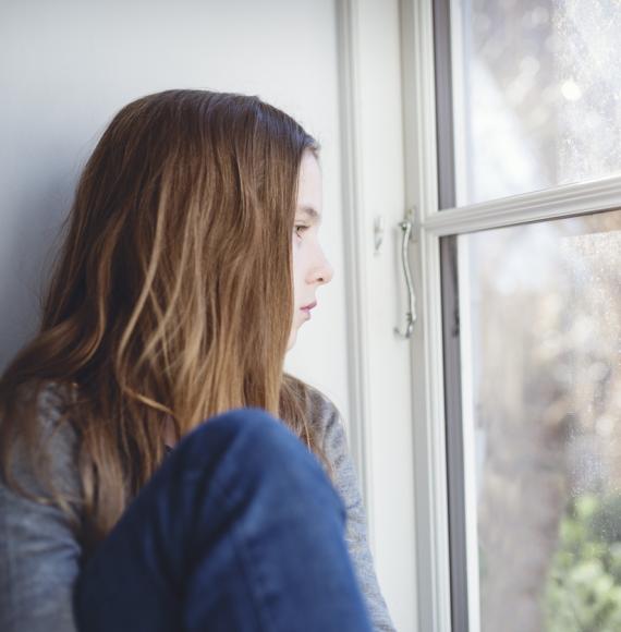 young girl looking out window