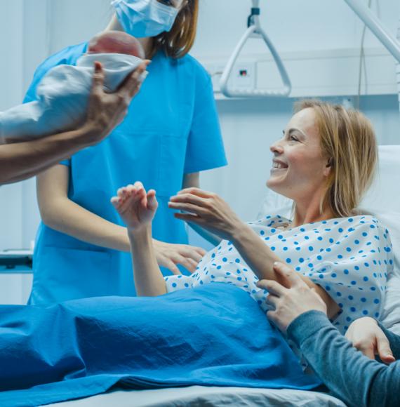 Midwife giving baby to mother