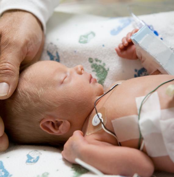 Father touching premature baby