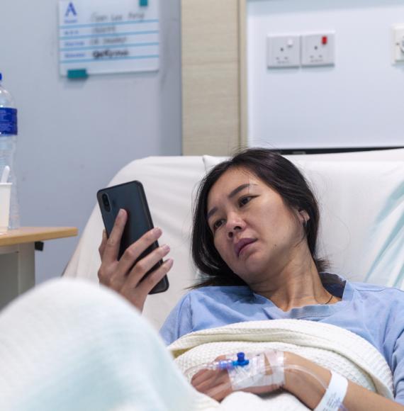 Female patient in bed on her phone