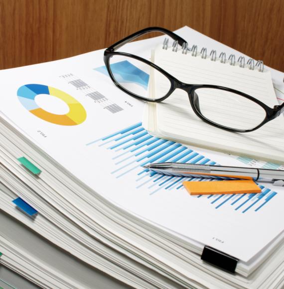 Glasses and pens on top of a stack of documents