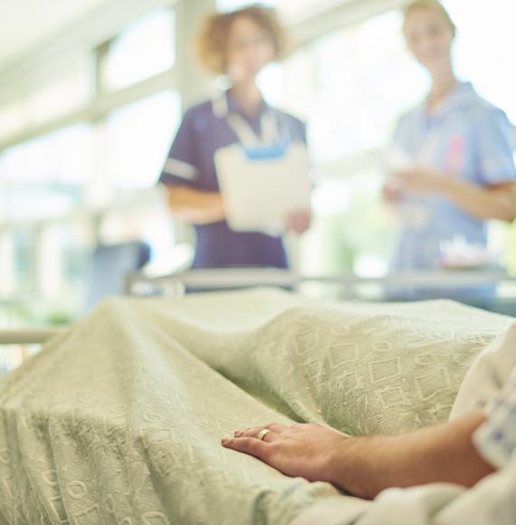 Patient in bed speaking to two nurses