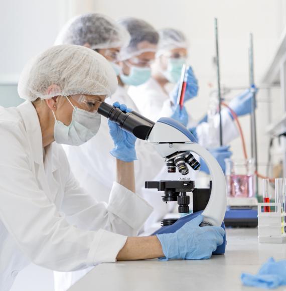 Scientists studying a virus by looking through a microscope