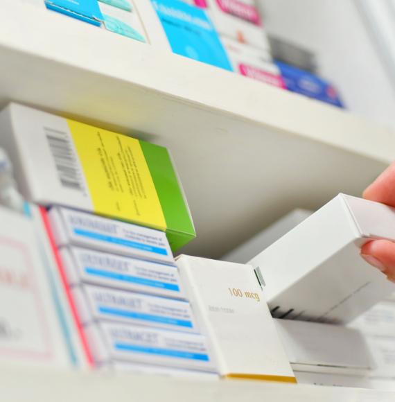 Close-up of a pharmacist's hand holding a medicine box