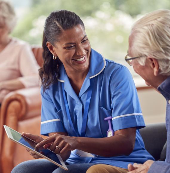 Senior Couple At Home With Man Talking To Female Nurse