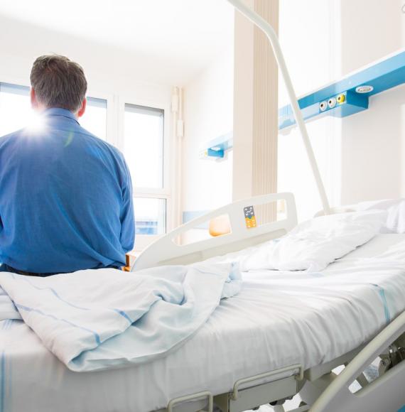 Man sitting on a hospital bed looking out of a window
