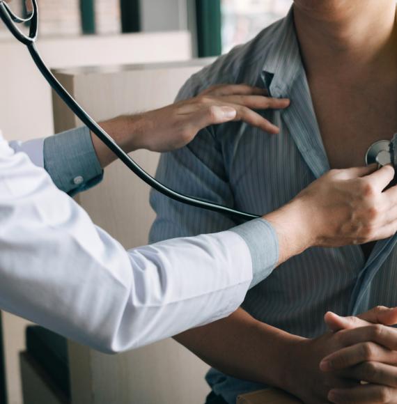 Doctor using stethoscope to check patient's heartbeat