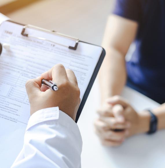 Doctor giving a prescription to a patient and filling out a medical form 