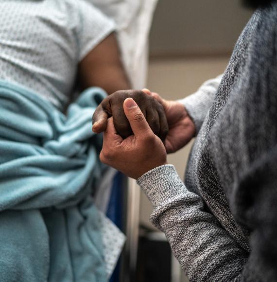 Son holding father's hand at the hospital