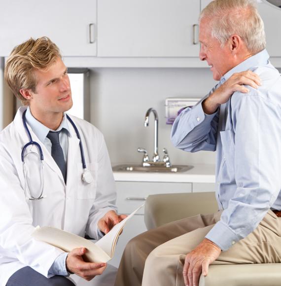 Doctor examining elderly male patient with shoulder pain