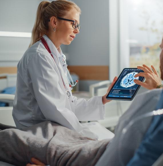 Female health professional tends to male patient on hospital ward