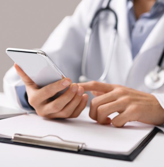 Doctor holding smartphone depicting online GP registration service and digital health