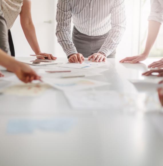 Group of professionals standing around a table brainstorming ideas 