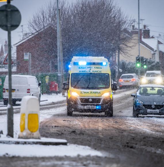 Ambulance driving through snow depicting the NHS winter pressures