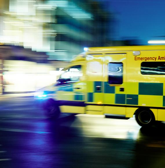 Side view of an NHS ambulance driving past quickly depicting future health emergencies 
