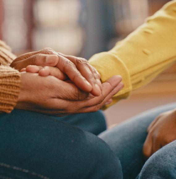 A person holding another person's hand to comfort them depicting mental health and suicide