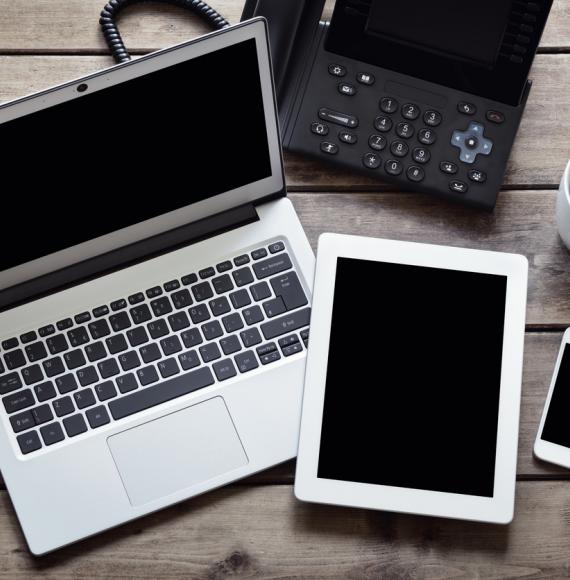 Overhead image of a laptop, tablet and phone depicting the NHS technology sector