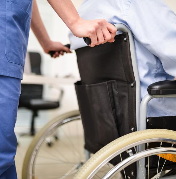 Nurse wheeling an elderly patient into hospital depicting a hospital admission